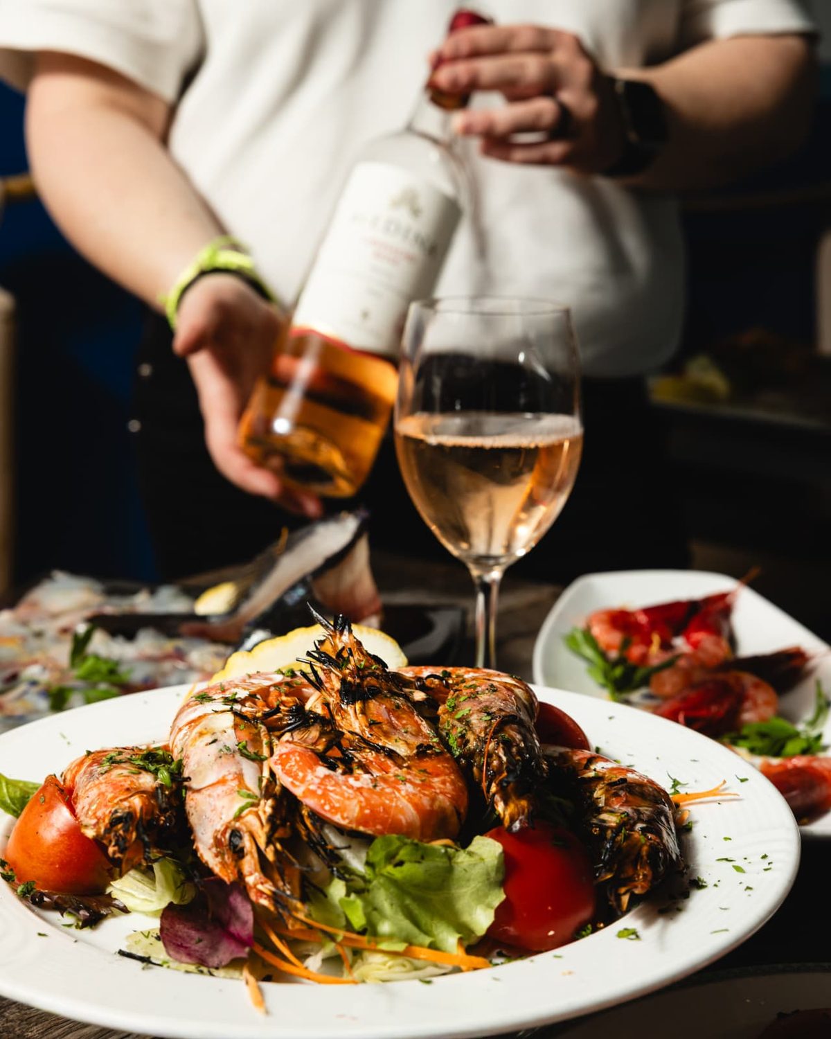 Rosé wine poured beside a plate of grilled prawns